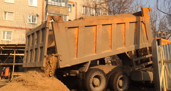 Самосвал разгружает песок